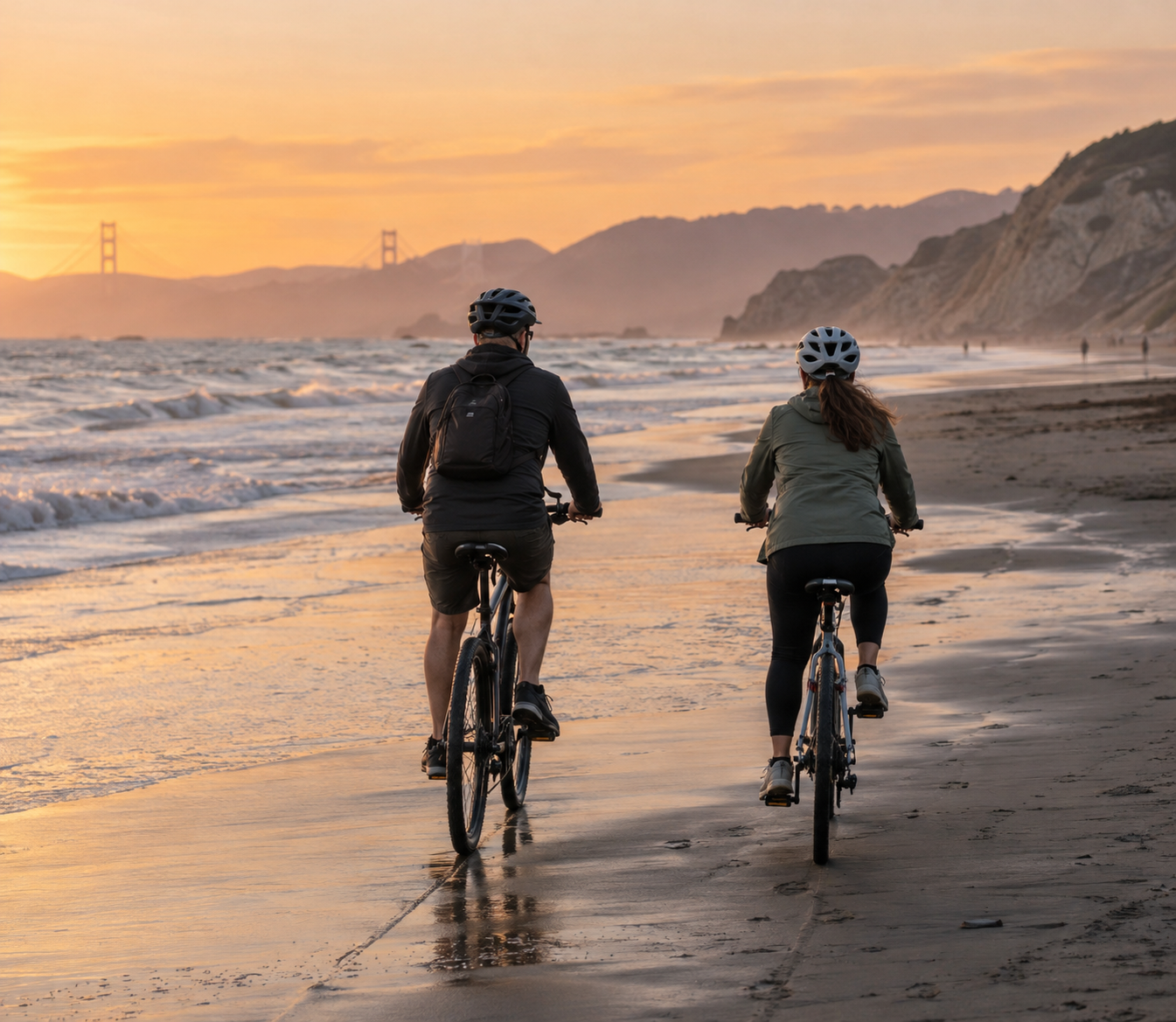 Two friends cycling beside the beach at sunset